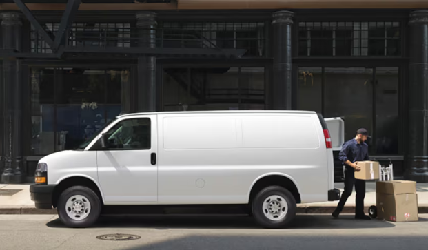 A delivery driver carefully loads packages into a white cargo van, activity protected by comprehensive commercial van insurance