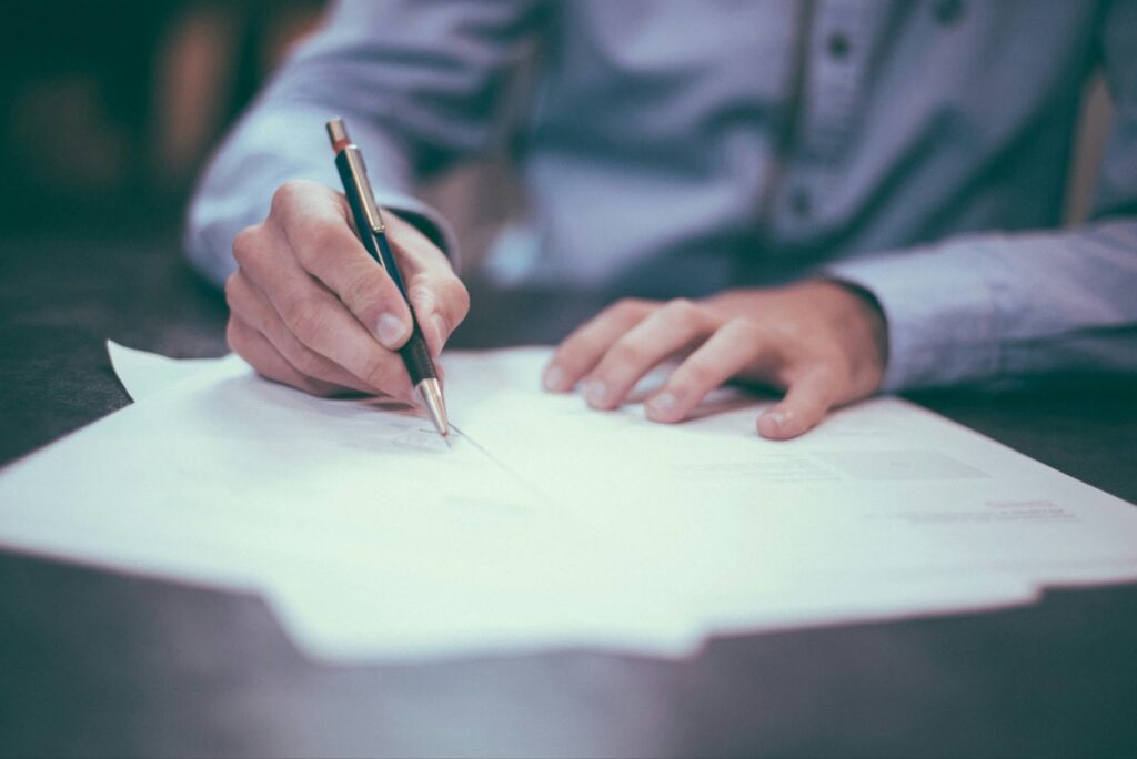 Una persona firmando documentos de seguro de vida después de explorar cuidadosamente sus opciones.